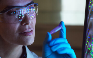Scientist analysing DNA samples in laboratory with digital data display