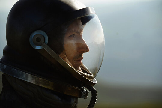 Astronaut wearing space helmet outdoors in profile view