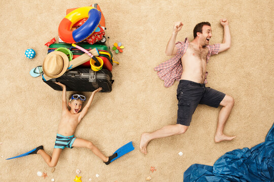 Father and son playfully posing with beach equipment in studio setting