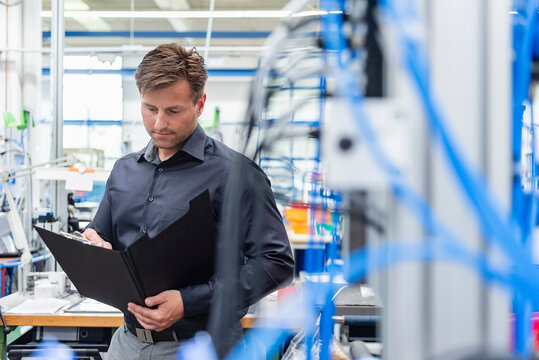 Engineer analyzing documents in modern production hall