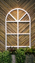 Creative garden patio featuring a white frame share with bamboo backdrop  and lush monstera plants.