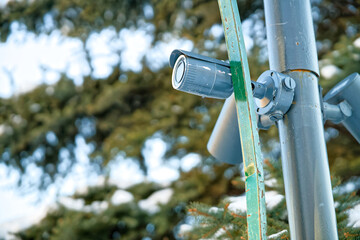 Close-up of a blue CCTV camera on a post guarding territory. Concept of safety, monitoring, and digital protection in a snowy city park during the cold season. Photo