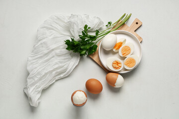 Plate with fresh boiled eggs and parsley on light background