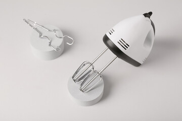 Plaster podiums with electric mixer and chrome beaters on grey background