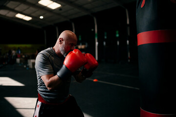 Boxing training with heavy bag at gym demonstrating stamina and focus