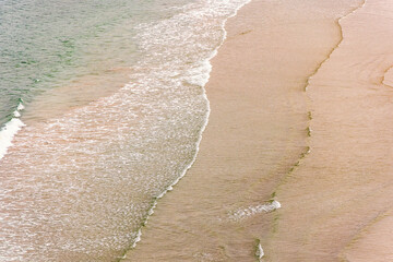 Aerial view at a sand beach with rolling sea waves