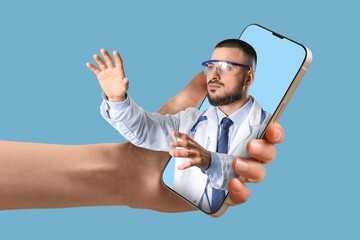 Fototapeta premium Patient holding smartphone with male doctor on screen against blue background. Concept of telemedicine