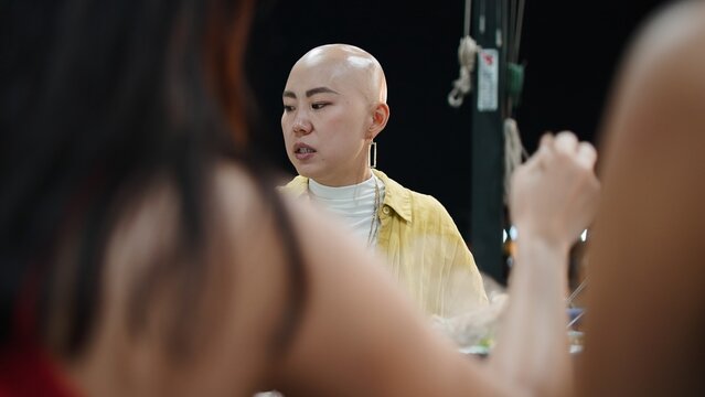 Thai friends dining at restaurant, bald woman enjoying traditional moo krata hotpot