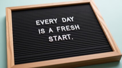 Black letterboard with wooden frame displaying the inspiring quote 'Every day is a fresh start.'