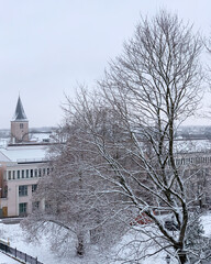 Snow-covered townscape with bare trees and steeple of St. John Church in Tartu, Tartumaa, Estonia, December 2020