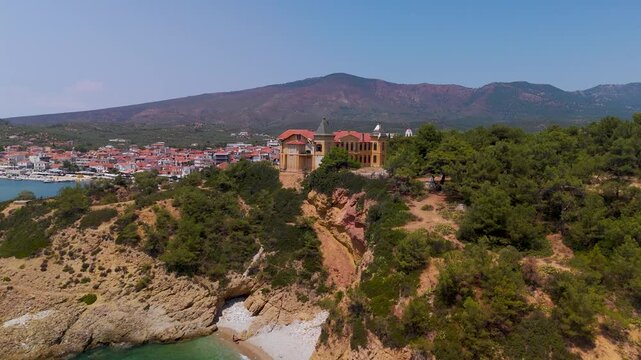 Aerial drone approach shot toward the historic Castle Speidel (Palataki) situated on the Limenaria coast of Thasos Island, Greece, under a bright summer sky.