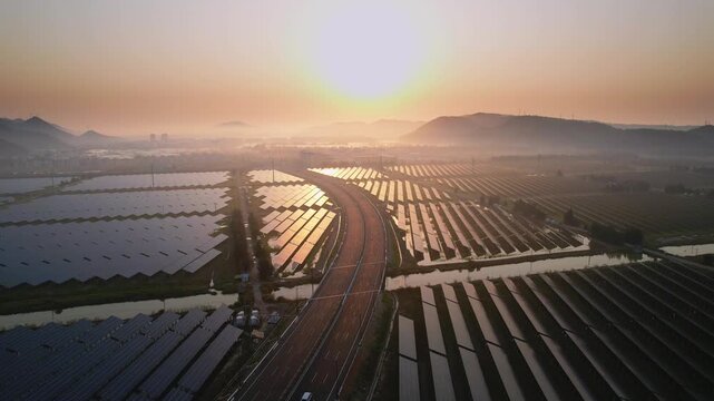 Solar power station and highway intersecting at sunrise with wetlands and distant hills