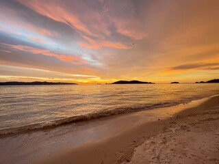 Beautiful sunset over sandy beach with colorful sky and calm sea, tropical coastal scenery
