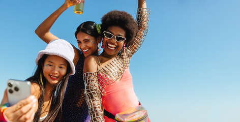 Friends take a sunny carnival selfie on the beach
