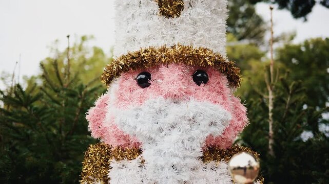 Decorative Christmas nutcracker soldier figure displayed outdoors with trees in the background