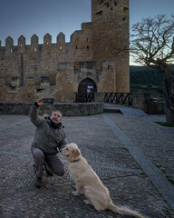 Happy man taking selfie with Golden Retriever dog at medieval Frias castle in Burgos Spain