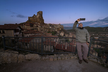 Man taking a selfie with smartphone at the medieval castle of Frias in Burgos Spain at sunset