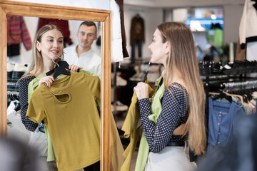 Couple young woman and young man choosing blouse in clothing store