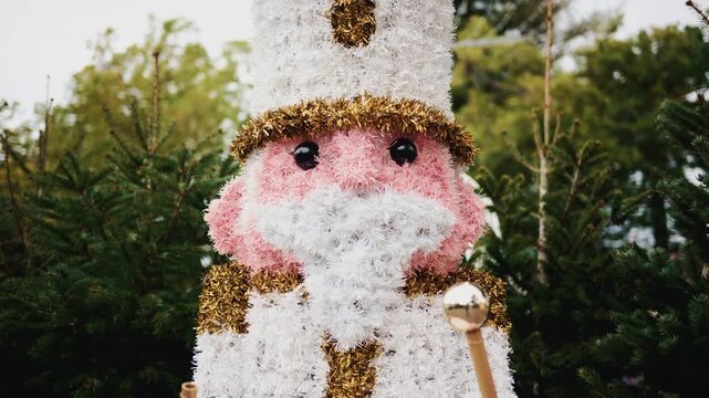 Decorative Christmas nutcracker soldier figure displayed outdoors with trees in the background