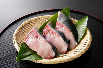 ざるに盛ったぶりの切り身（葉蘭・黒背景）