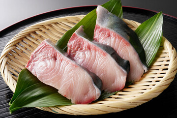 ざるに盛ったぶりの切り身（葉蘭・黒背景）