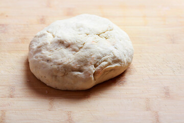 Freshly prepared dough lying on wooden table.