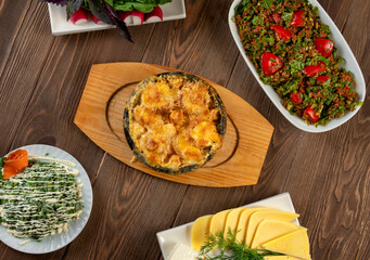 Casserole with mushrooms and
meat, cheese, salad and vegetables on a wooden background