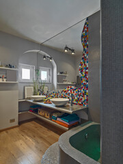 interior view of a modern bathroom with a wooden floor while in the background you can see the washbasins with a large mirror