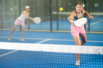 Portrait of cheerful girl paddle tennis player during friendly doubles couple match at court
