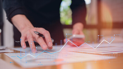 Business professional analyzing documents with digital growth chart overlay. Concept of financial performance, data analytics, KPI tracking, investment strategy, and business growth planning