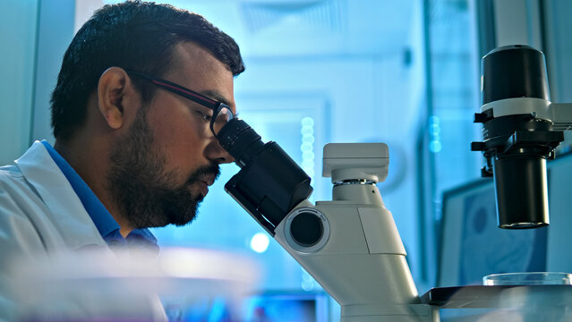 A researcher examines a sample under a microscope in a modern lab, highlighting meticulous scientific investigation and precision in medical research.