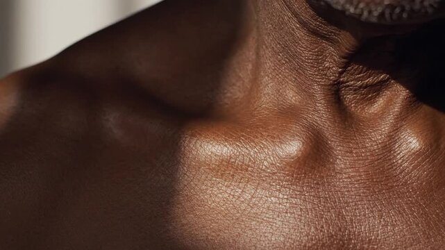 Close-up on dark skin toned, glistening with sweat or oil, contrasting light and shadows, highlighting skin texture and