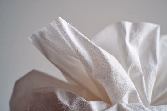 Close up of a used white tissue folded neatly, soft daylight, neutral background, quiet vulnerability