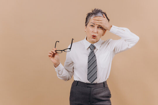 Mature businesswoman feeling stressed and forgetting important tasks on beige background