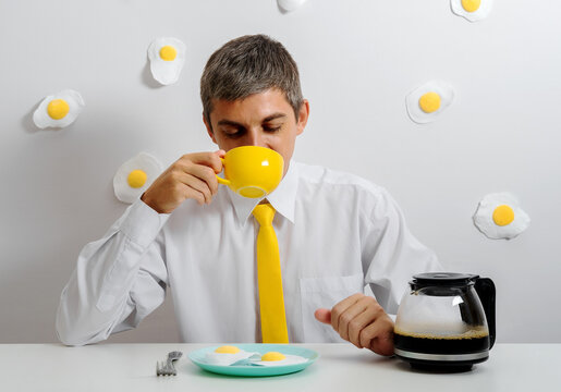 Office worker in white shirt and yellow tie having humorous surreal breakfast