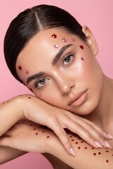 Valentine beauty portrait with heart rhinestones on pink background
