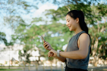 Women pausing during run, checking fitness progress in smartphone