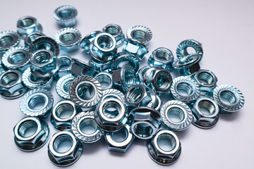 Pile of zinc-plated serrated flange hex nuts on a white background.