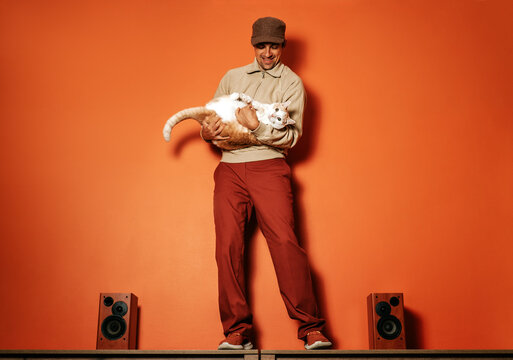 Man dancing with cat and music speakers in retro orange setting