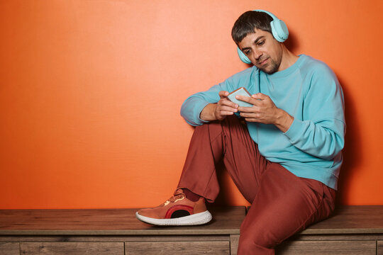 Person with wireless headphones using phone in casual setting