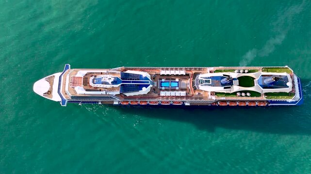 Aerial drone view of a large cruise ship sailing across calm blue ocean waters under clear sky vessel moves steadily through the sea symbolizing luxury travel  tourism maritime transportation and ocea