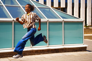 Person running in urban setting wearing casual jeans and striped shirt