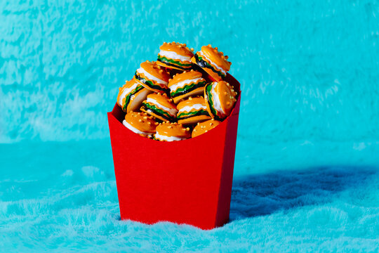 Mini burgers stacked in red container against turquoise fur background