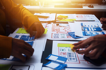 Team of uxui designers pointing at computer screen, discussing new mobile app design in the office