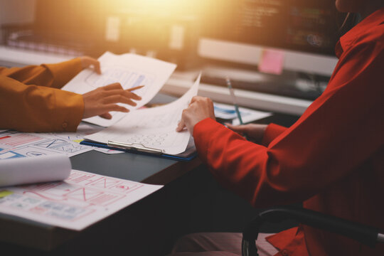 Team of uxui designers pointing at computer screen, discussing new mobile app design in the office - Powered by Adobe