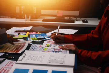 Team of uxui designers pointing at computer screen, discussing new mobile app design in the office