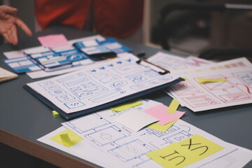 Team of uxui designers pointing at computer screen, discussing new mobile app design in the office