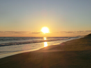 波間に反射する夕日と穏やかに打ち寄せる波