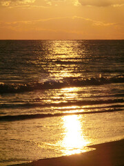 打ち寄せる波に反射する夕日