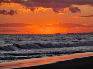 打ち寄せる波とオレンジ色に染まる夕焼け空